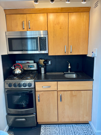 Kitchen with gas stove top and gas oven, microwave, full size refrigerator, and ample storage. - Comfortable, convenient studio one block from Cleveland Park Metro (Red Line)