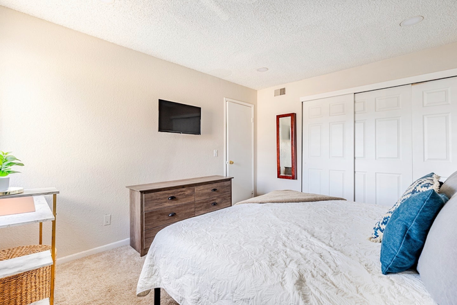 Primary bedroom with smart TV and full length mirror - Furnished 2BR Condo Near Anschutz Medical Campus
