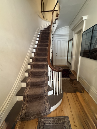 Building entry hallway - original 1851 staircase with winding banister, painted balustrade, dark treads and wool carpet runner. - 61 OTIS — Furnished Historic Residence, East Cambridge near Kendall Square Townhome