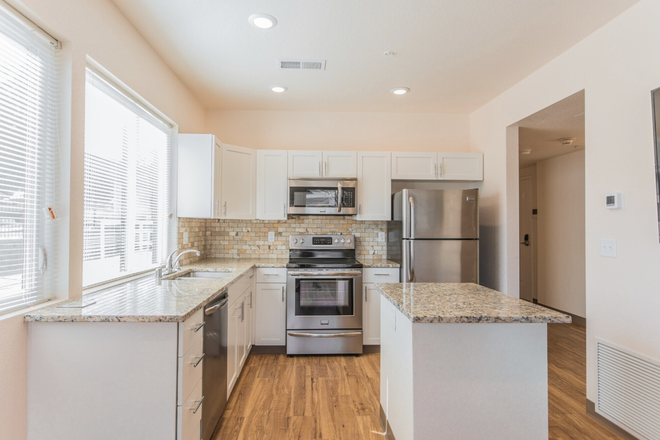 Kitchen with full fridge, wine fridge, dishwasher, and sink - The Block Apartments