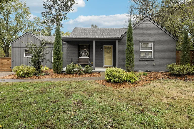 Front view of the home with covered porch and large yard. - Spacious Dog-Friendly 3BR House with Huge Garage & Fenced Yard Near Two Rivers