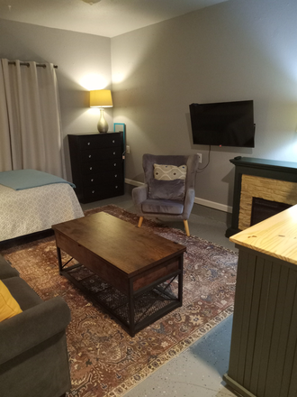 Living area and bedroom with a 5 drawer dresser. - FULLY FURNISHED, ALL UTILITIES PAID, MOVE-IN READY Apartments
