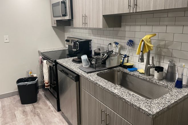 View of kitchen: sink, dishwasher, stove, and microwave. - The 9 at College Park Apartments, 1 bed 1 bath in a shared suite