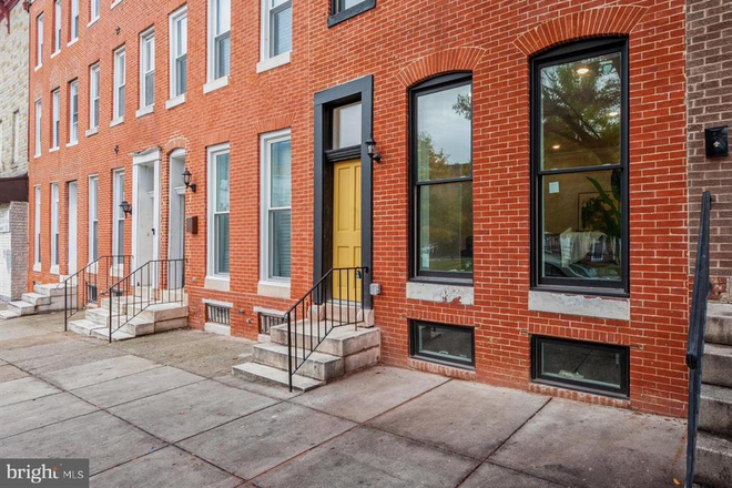 Front of home with oversized beautiful wooden mustard door - Spacious and charming multi-level rowhome in 5-min walking distance to Johns Hopkins Medical Ca