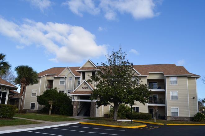 an apartment building with a tree in front of it - Tivoli Orlando Apartments