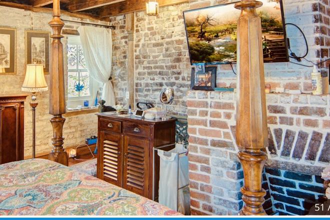 Gorgeous bedroom with exposed wood beams, and brick. Attached bathroom with walk-in shower. - Rutledge Carriage House