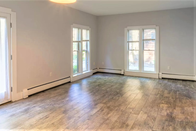 Open living/dining room, tall windows and french doors to patio - 3-BR Townhouse Apartment on Quiet Tree-Lined Street, Red Line