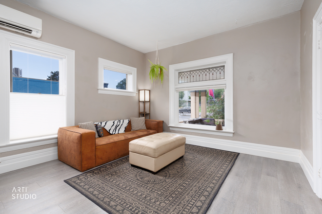 Comfy spot to relax or work, with easy power: a lamp charging station and a surge-protected strip right by the couch. - Furnished 2BR/2BA, 6 Blocks to Campus, Both Ensuite, Utilities Included, Academic-Year Lease Apartments