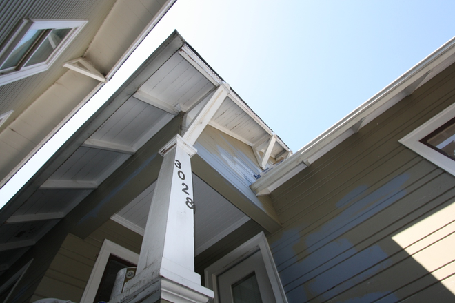 front - Wonderful redwood framed home with wooden shutters and peaked roof on tree lined street.