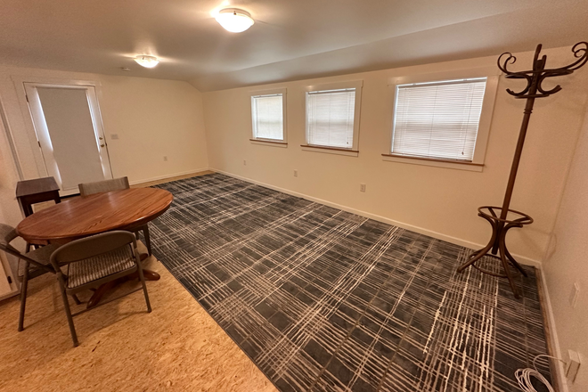 View of the main space from the entrance. 3 windows facing southwest, and a vintage rack for hanigng coats and bags. - Studio apartment close to campus