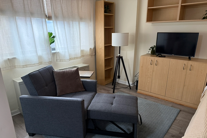 living room area with recliner chair and TV, built-in shelves - Bright, convenient studio in the heart of DC - Apartments