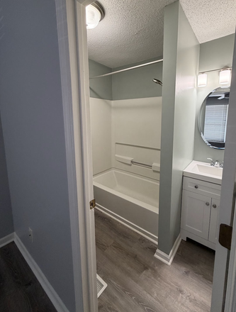 View into the private bathroom highlighting the updated vanity, modern circular mirror, and bright lighting. - Private BR/Bath for Rent in 2BR Condo - All-Inclusive & Direct Bus to UNC