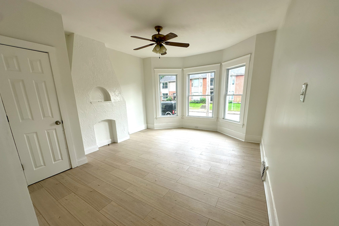 Spacious living room with bay windows, chimney detail, and closet - Huge, sunny, renovated 2BR near campus