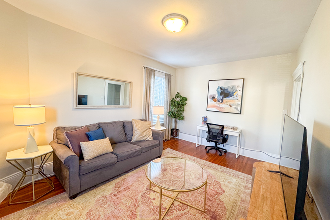 Living room, has a small desk great for setting up your laptop - WAS6364 Furnished 1-Bed w/ Natural Light,  Centrally Located-MBTA Apartments