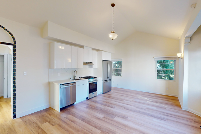 Living room with a window, wood-like flooring, and a view of the kitchen - 2363 Le Conte Apartments