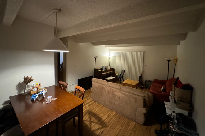 Common area with dining table, two sofas, a piano, and an electric guitar. - Newton Court Apartments