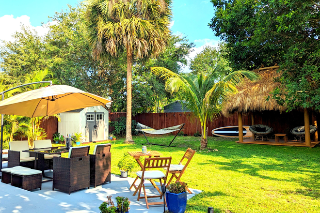 Backyard with Tiki hut, palm trees, hammock - Modern Cottage-Style House with Large Backyard