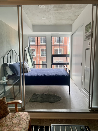 Bedroom has floor-to-ceiling windows - Furnished 1-Bedroom Condo with Ensuite Laundry in King West