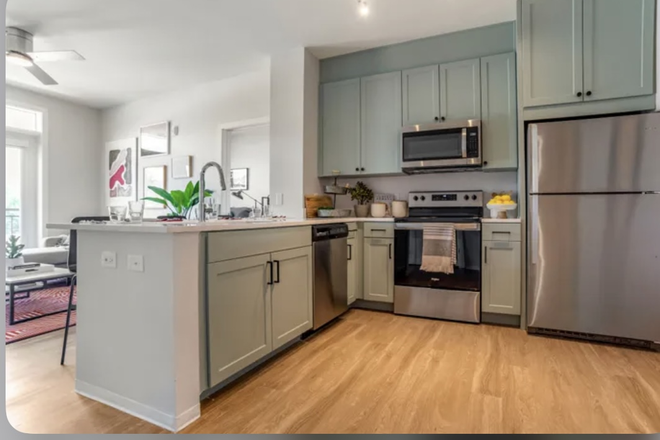 This modern kitchen features sleek stainless steel appliances, including a refrigerator, dishwasher, microwave, and oven, perfect for cookin - Union Tuscaloosa Apartments