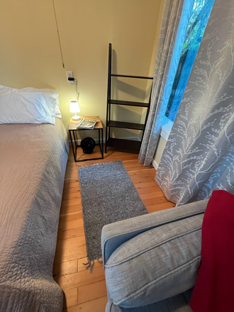 End of sectional, bedside and large window. - Cabin Atelier Apartments