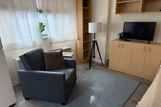 living room area with recliner chair and TV, built-in shelves - Bright, convenient studio in the heart of DC - Apartments