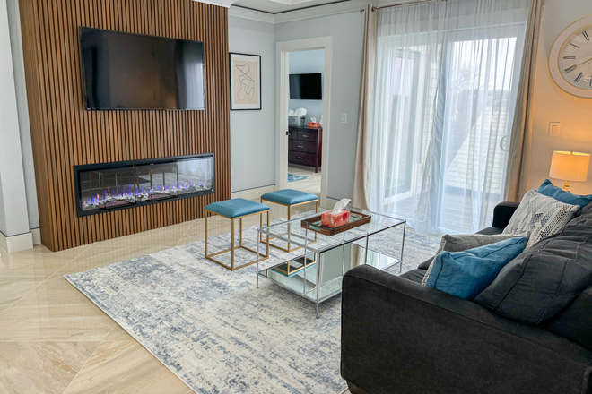 Mounted TV for easy viewing, just above the fireplace, door to outdoor deck - TRA313 3-bed 2-bath w/ Stunning Boston Skyline View Apartments