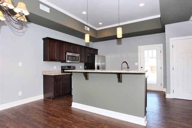 Open kitchen with stainless appliances - End-Unit Craftsman Style Townhouse in Cornerstone