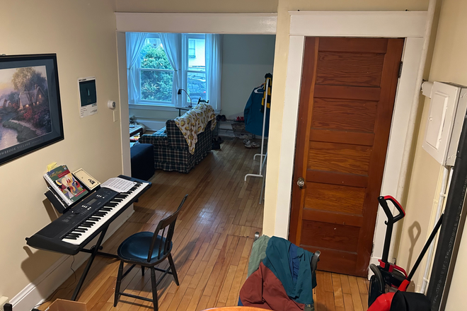 This is the living room. The chair with clothes on it contains the dinner table with 4 chairs. - 20 Hungerford Terrace Apartments