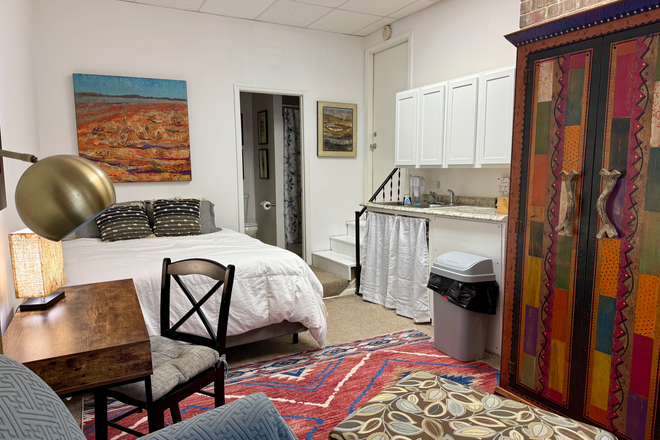 main room with desk, comfy chair, armoire. kithenette, queen bed with memory foam mattress - Paper Cat Retreat and Studio Apartments