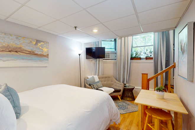 Bed, wall art, lounge chair, mounted TV, table with stools, window - BEA1029A Furnished Studio on MBTA-Fenway, Longwood, BC, BU Apartments