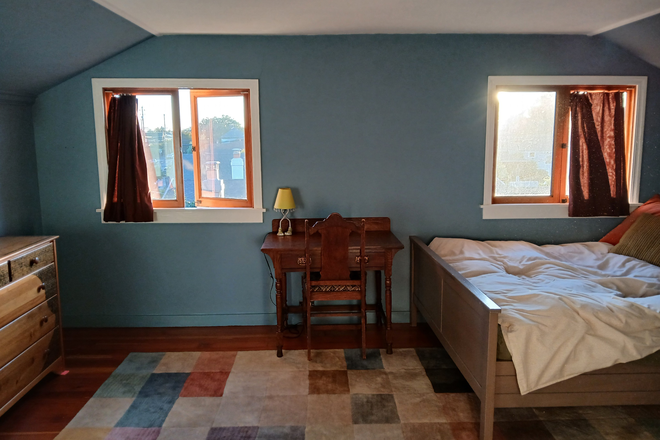 Light-filled bedroom facing west with queen-sized bed and desk and chair - Roomy furnished room in private house. Near public transportation.
