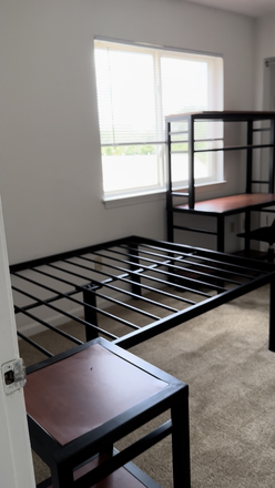 Bedframe, bedside table, and large window - The Fox Townhomes