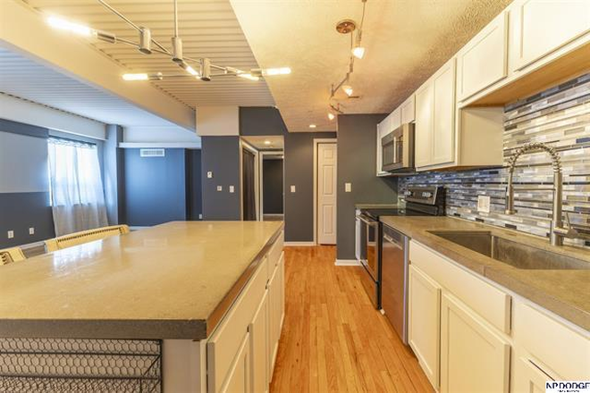 Modern kitchen featuring white cabinetry, stainless steel appliances, tile backsplash, and peninsula seating. - Modern, Move-In Ready Midtown Condo Near Major Campuses & Medical Centers