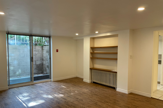Living room with bookshelves and East facing Patio doors - Spadina & Davenport ( M5R 2Y3 ) House