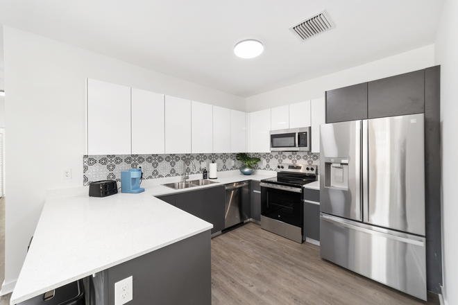 Modern kitchen with full-size fridge, quartz countertops, and plenty of storage space - Brand-new townhouse (3/3.5); utilities & parking included!