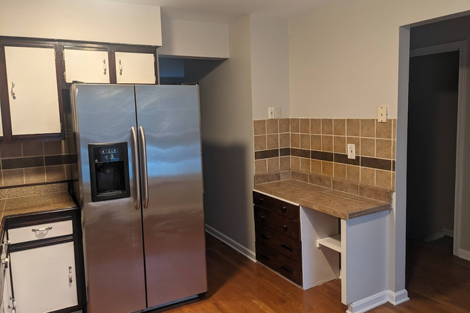 Modern kitchen featuring stainless steel refrigerator and ample cabinet storage - 3 Bedroom + Bonus room with fenced yard close to campus Townhome