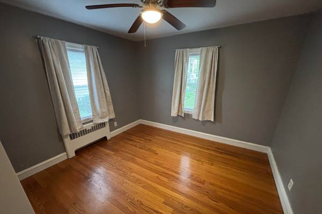 Bedroom with curtains and hardwood floor. - Nice East Side Apt. Share. Parking and Laundry Included!