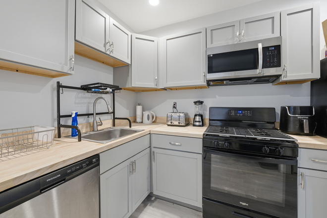 Close-up of kitchen appliances, including dishwasher, gas stove, microwave, and updated cabinetry. - 6 Bedroom Renovated Temple Student Housing – 2 Minute Walk to Campus! House
