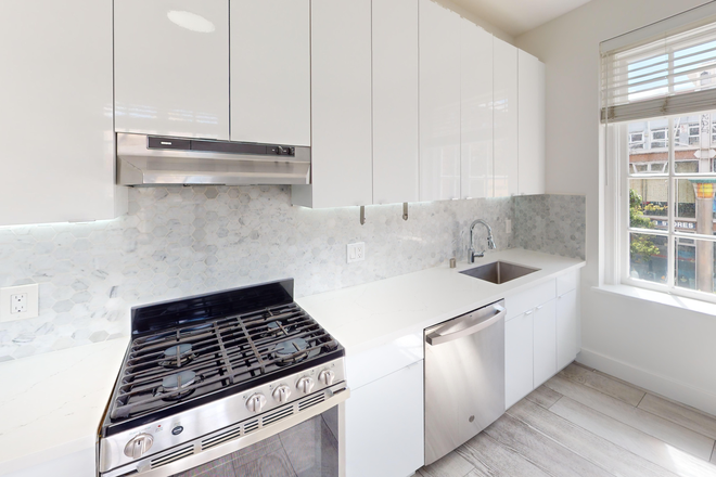 Kitchen with multiple cabinets, stove, range hood, and sink - 2500 Durant Apartments