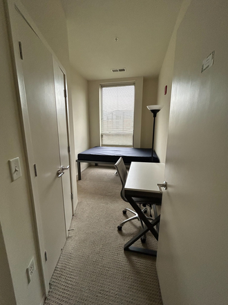 Bedroom with full size bed, desk, chair, lamp, and full size mirror behind door - DISCOUNTED Terrapin Row Apartments, Building 1 SPRING 26