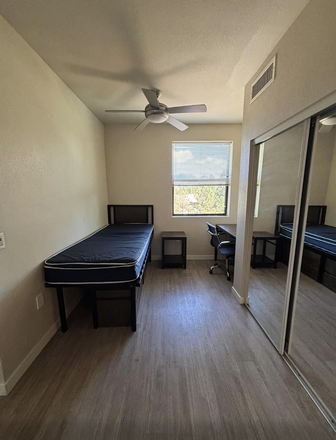 Bedroom with included bed, nightstand, and desk with a spacious closet - The Suites Apartments