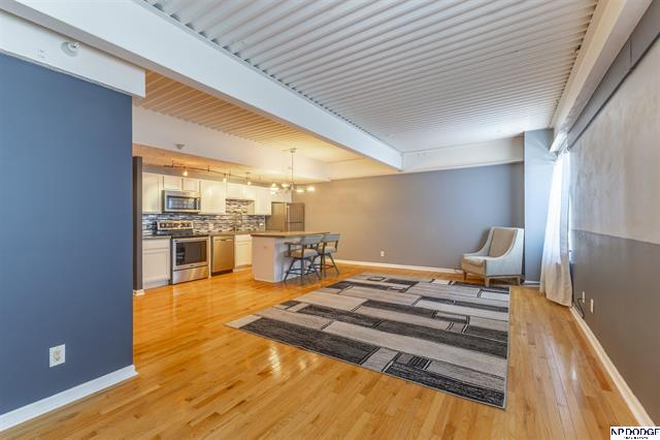 Open-concept living space with hardwood floors and a seamless flow into the kitchen. - Modern, Move-In Ready Midtown Condo Near Major Campuses & Medical Centers