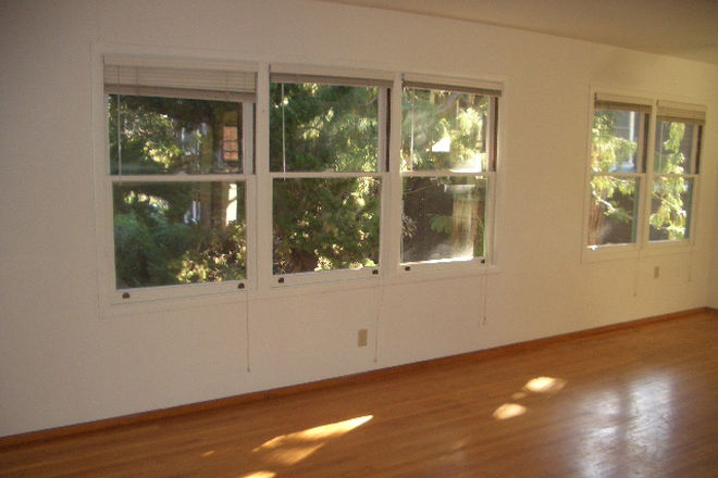 living room open to dining area with 3 east facing windows - Peaceful Top Floor 2-Bedroom Available in New Year Apartments