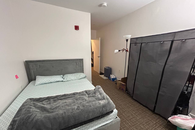 ANgular view of queen bed, storage for clothes and entry - Unit 1 Apartments