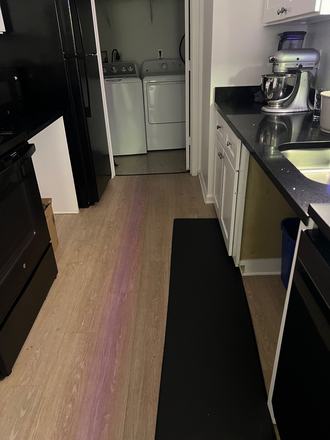 Another view of the kitchen. You can see the hardwood floors and the laundry room in the back. - Courtyards at UMD Apartments