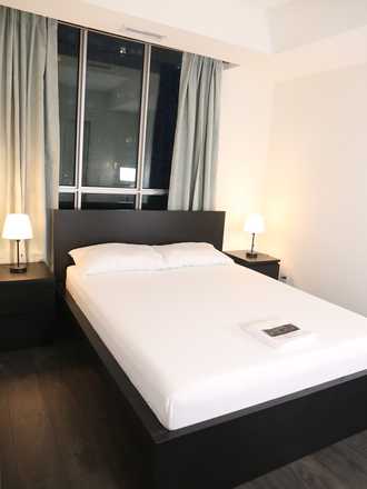 Bedroom with large bed bracketed by two side tables with lamps, new mattress, pillows, mattress cover. - 1 Bedroom Apartment Fully Furnished Turnkey UofT UTSC OCMT