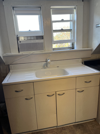 Kitchen sink, window air conditioner, work space and lower cabinets. - Apartment with One Bedroom in quiet owner-occupied house, 3rd Floor, with private covered porch.