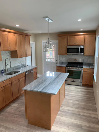 Kitchen with island, gas range, and dishwasher. - Two available bedrooms in a three-bedroom, second-floor JP apartment