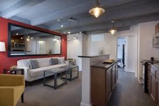Shared living room. Comes with couch, television, and a coffee table. Kitchen can be seen on far left. - Sterling Boulder Apartment
