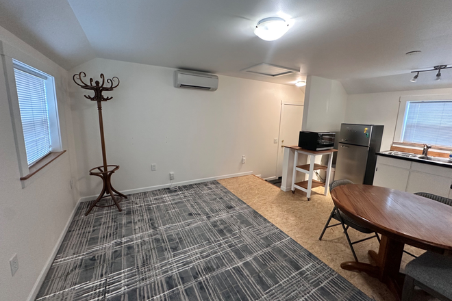 View of the kitchenette and the entrance. Including air condition unit, kitchen appliances, and main table + chairs - Studio apartment close to campus